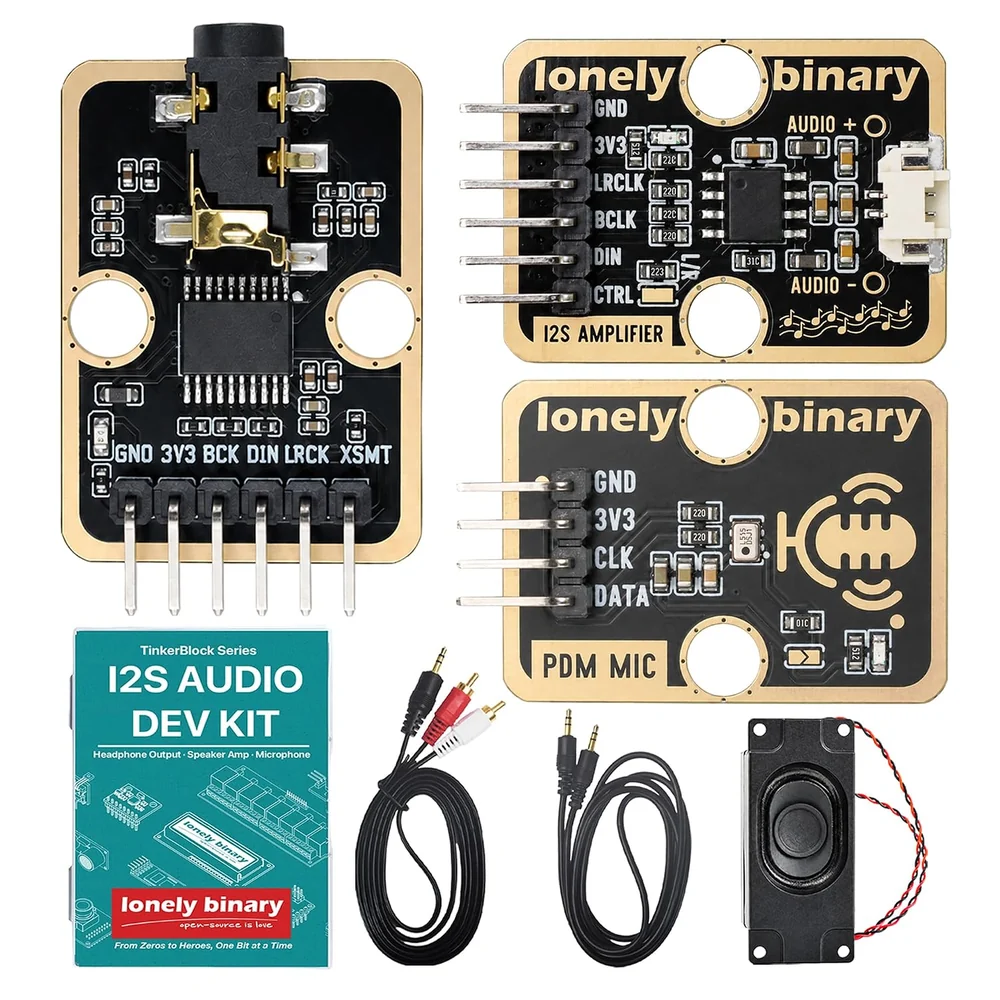 The I2S audio kit laid out: the TK103 DAC on the left with its headphone jack at the top and six pins along the bottom printed GND, 3V3, BCK, DIN, LRCK and XSMT; the TK100 amplifier and TK101 microphone on the right; a teal box printed I2S AUDIO DEV KIT; a 3.5 mm to RCA cable, a 3.5 mm to 3.5 mm cable, and a small black speaker with red and black wires.