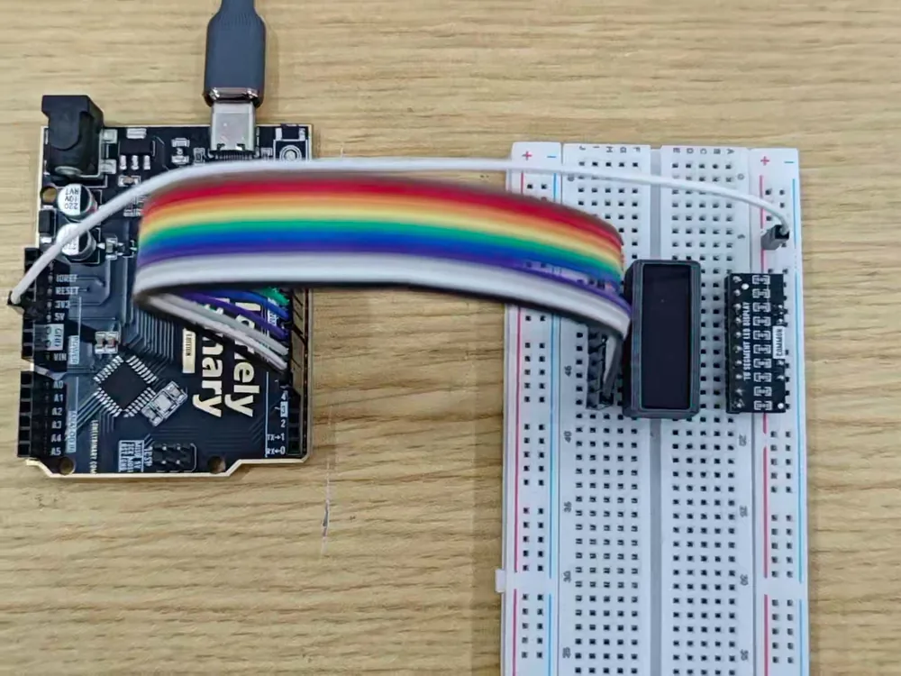 A breadboard with a bar graph straddling the centre channel and a resistor array board plugged in beside it, a ribbon of ten coloured jumper wires running from the bar to pins D4 to D13 on an Uno, and a single white wire from the board's COMMON row back to the Uno's 5V pin.