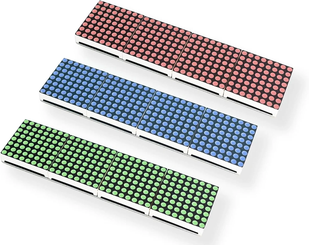 The three boards seen at an angle from above, unlit: one with red LEDs, one with blue and one with green, each a strip of four separate 8 by 8 matrix packages butted end to end with visible seams between them.
