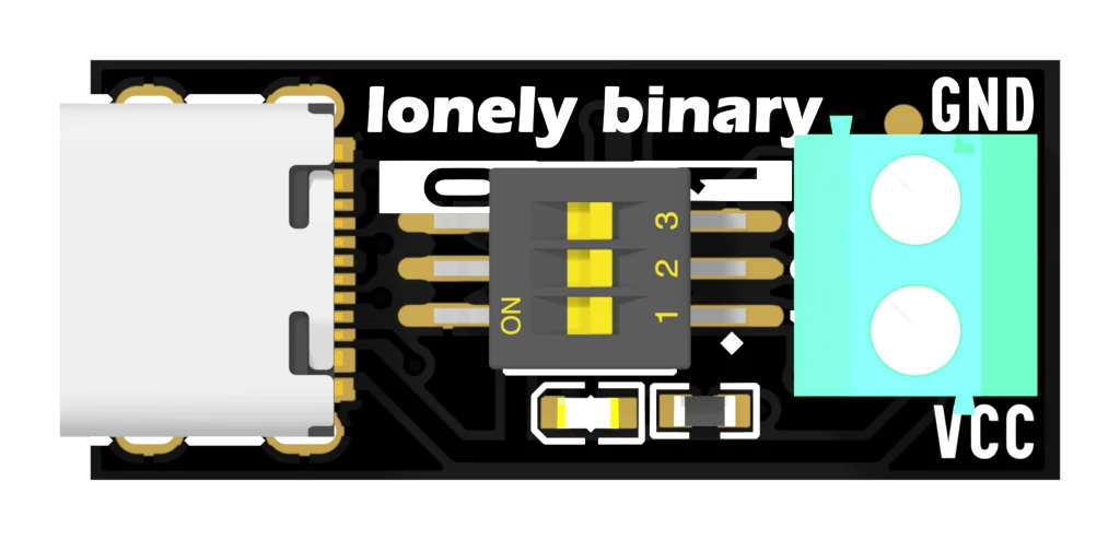 The top of the trigger board: a white USB-C socket at the left, the words lonely binary in white across the top, a three-position DIP switch in the middle with a white bar behind it printed 0 at one end and 1 at the other, a small red LED below it, and a mint-green screw terminal at the right with GND printed above and VCC below.