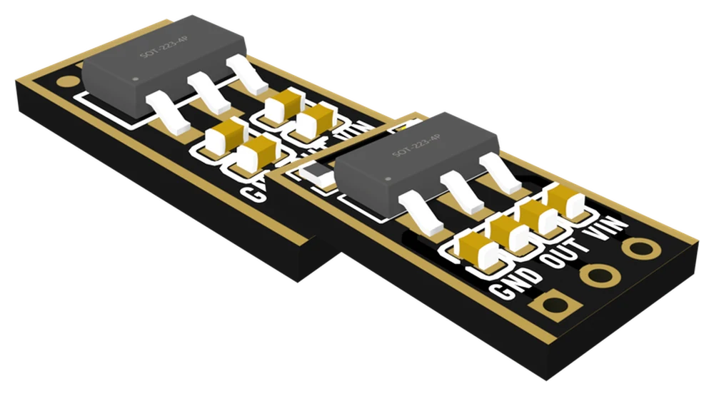 Two AMS1117 regulator boards at an angle, black with gold edges: the 3.3 V board in front with its chip, four small capacitors and three holes labelled GND, OUT and VIN, and the adjustable board behind it with the same layout and no LED.