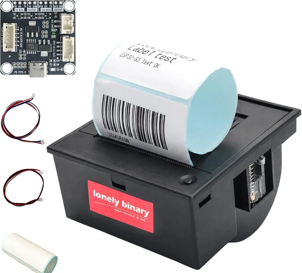 The label printer kit: a square black printer module with a printed label curling out of the top reading Label test above a barcode, the Type-C TTL base board above it, a roll of labels, and two JST cables — one two-wire for power and one five-wire for serial.